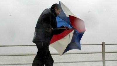 Man struggling to open umbrella during stormy weather