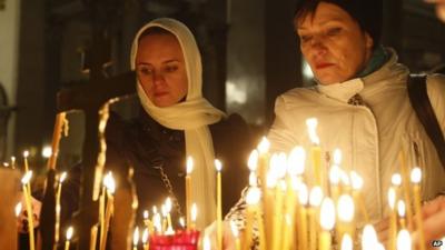 People light candles inside a church in St Petersburg, Russia