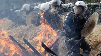 Belgian riot police near burning hay