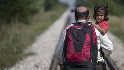 A man hoping to cross into Hungary, carrying a child just outside the village of Horgos in Serbia