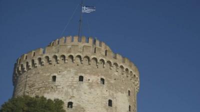 The Greek flag flying above a tower in Thessaloniki