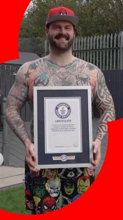 A man proudly standing with a certificate from the Guinness book of world records 