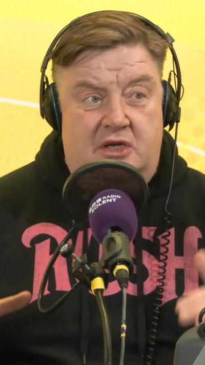 Adam Blackmore speaks into a purple microphone and wears headphones. 