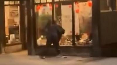 Man taking bottles from shop window