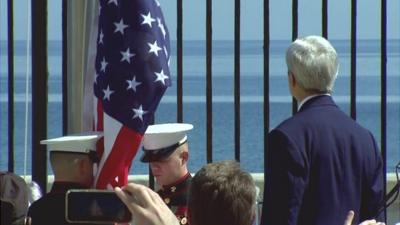 John Kerry looks on at US flag