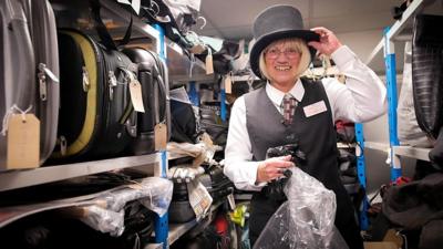 Gill Miles wearing a lost top hat at Transport for Wales' lost property office in Newport