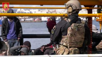 A Maltese soldier stands by migrants onboard Elhiblu 1