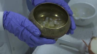 Person holding a bronzed bowl with liquid inside