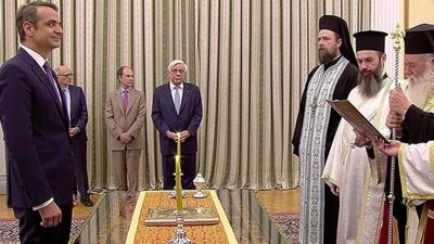 Kyriakos Mitsotakis stands in front of a group of Greek Orthodox priests