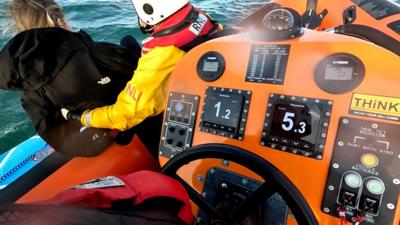 Woman being helped into lifeboat