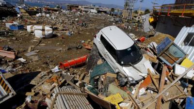 A damaged car lies on debris in Coquimbo city