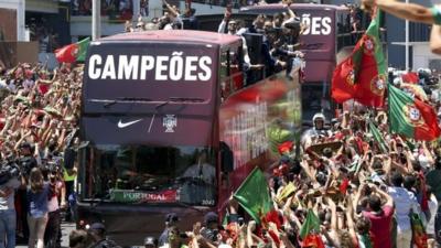 Thousands of supporters cheer the players of the Portuguese national soccer team on an open-top bus along the streets of Lisbon