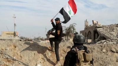 A member from the Iraqi security forces holds an Iraqi flag in the city of Ramadi