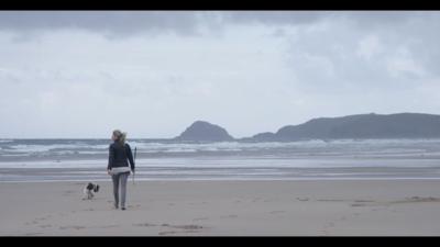 Woman on the beach carrying a golf club