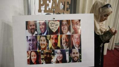 A Muslim woman writes a message near a photo of the 14 victims in the San Bernardino attacks
