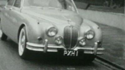 Black and white still from footage shows a car