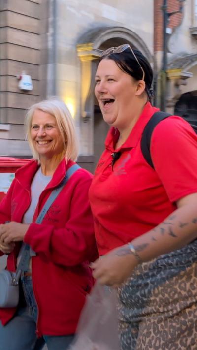 Two people in red clothing walking along a city street.