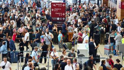 A large group of people waiting in an airport to hear news about their flights.