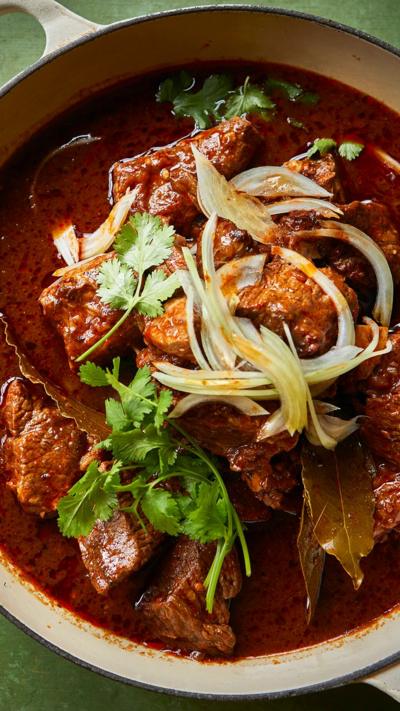 Top down view of beef in a sauce in a double handled dish