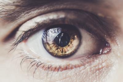 Close-up image of an eye, the camera can be viewed in the pupil's reflection