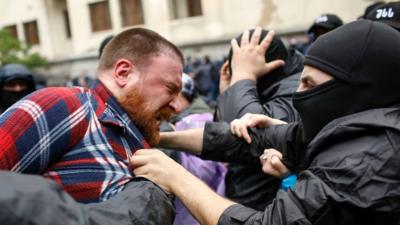 Man looks angry as he is grabbed by police officer