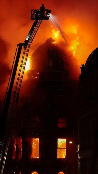 Forsyth building in flames with fire services crane spraying water on it