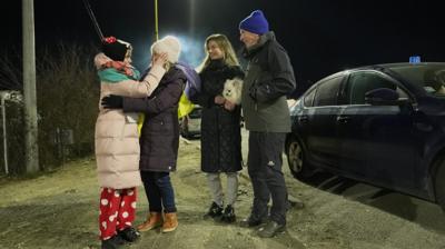 four family members in winter clothing being reunited on a snowy pavement