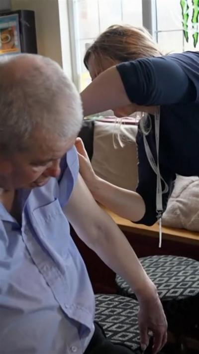 A man in a light, button-up shirt getting a jab from a person in a navy shirt.