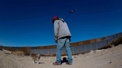 Man in front of Mexican border wall