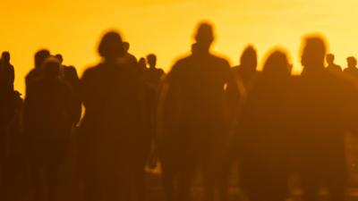 Silhouettes of people walking towards the sunset