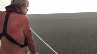 Sailor Tom Whitehead looking at sea of pumice on a boat in the Pacific Ocean