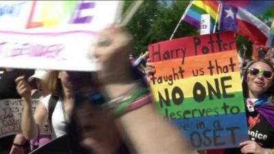 A marcher with a poster saying 'Harry Potter taught us that no one deserves to live in a closet'