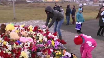 A woman and a small girl laying flowers at a shrine