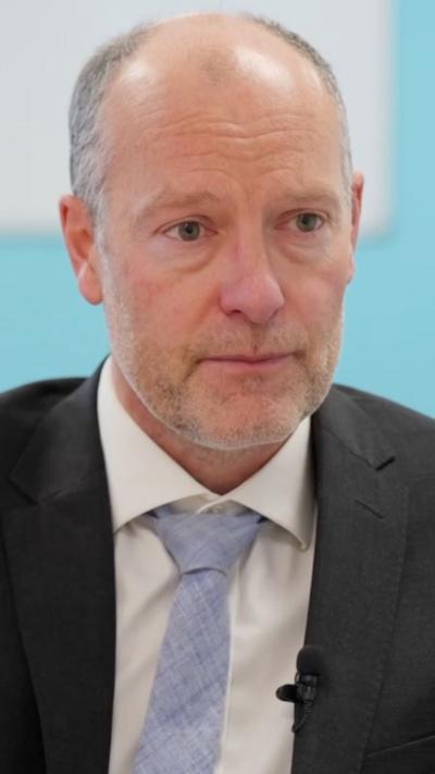 A man wearing a black suit jacket and white shirt
