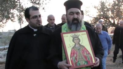 Priest holding picture of Saint Barbara