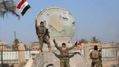 A member of the Iraqi security forces holds an Iraqi flag in the city of Ramadi