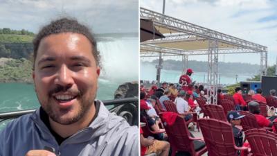 A presenter talks to camera in front of Niagara Falls on the left, with people seated in rows of red chairs on the right.