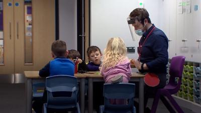 Children and teacher around desk