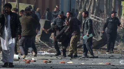 Afghan volunteers and policemen help wounded at the scene of the car bomb in Kabul