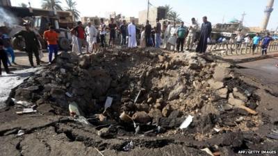 Iraqi men look at a crater left by a massive suicide car bomb