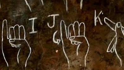 Sign language fro the letters I,J and K on a chalk board