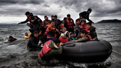 Migrants help other refugees and migrants to land on the Greek island of Lesbos