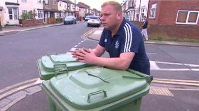 Man leaning on wheeled bins