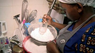 woman sieving sugar in bowl