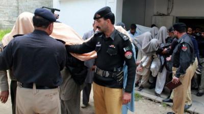 People with heads covered, accompanied by police