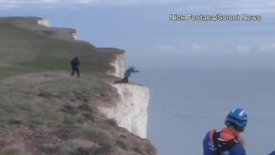 Base jumper leaping off cliff