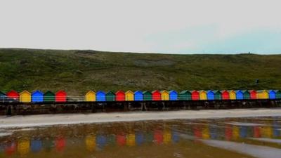 Cloudy and grey coastal scene wih multi-coloured beach huts