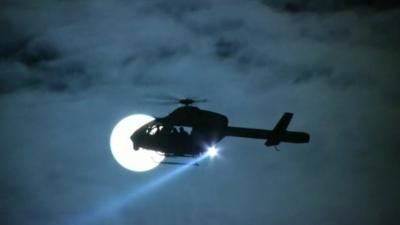 Helicopter silhouetted against Moon