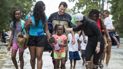 The Walker and Brown families walk out of the water at Memorial Drive and North Eldridge Parkway in the Energy Corridor of west Houston, Texas