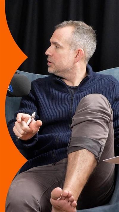 Dr Chris van Tulleken is looking to his right. He is wearing brown trousers. His left trouser leg is pulled up to show his foot.